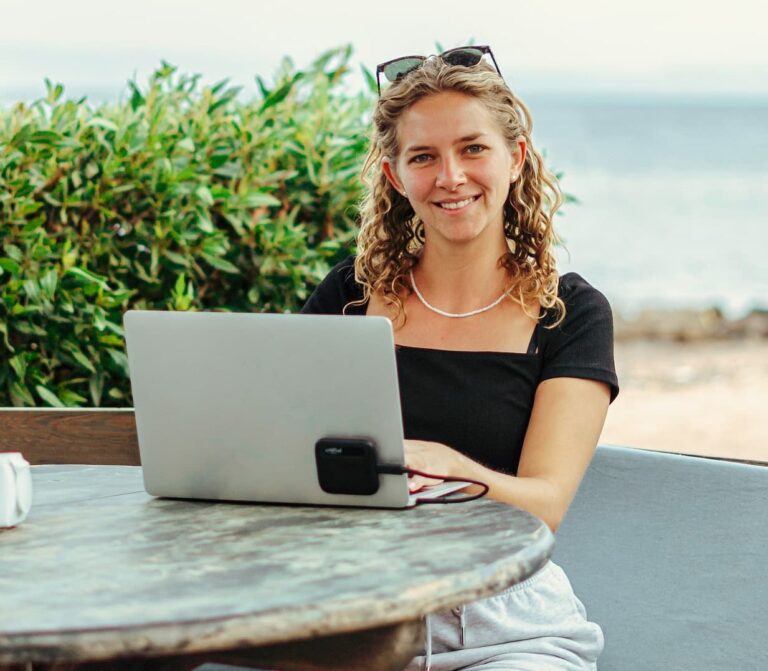 Glückliche Buchhalterin arbeitet mit Notebook am Strand